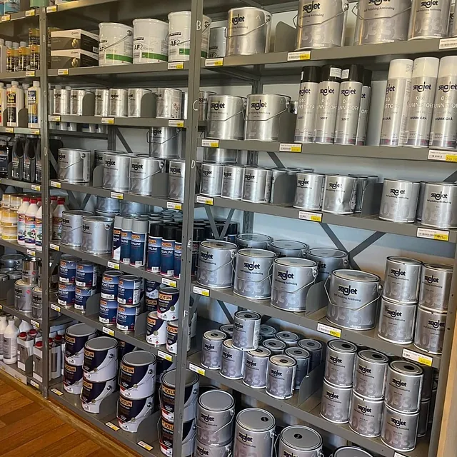 Hyller fylt med båtpleieprodukter og maling i bokser og spann, organisert etter type og merke.